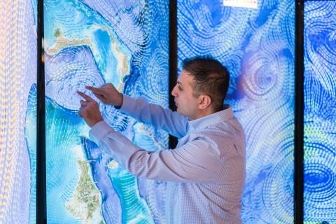 Erol Aygar conducts data visualization research at the Center for Coastal and Ocean Mapping in Durham for his master's thesis using a giant colorful screen wall projection.